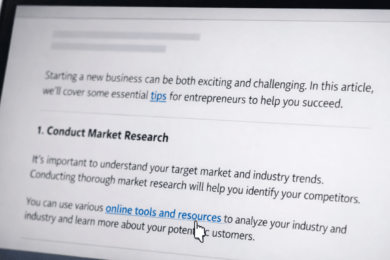 Close-up of a laptop screen showing a blog article with highlighted clickable anchor text and a cursor hovering over a link preview URL